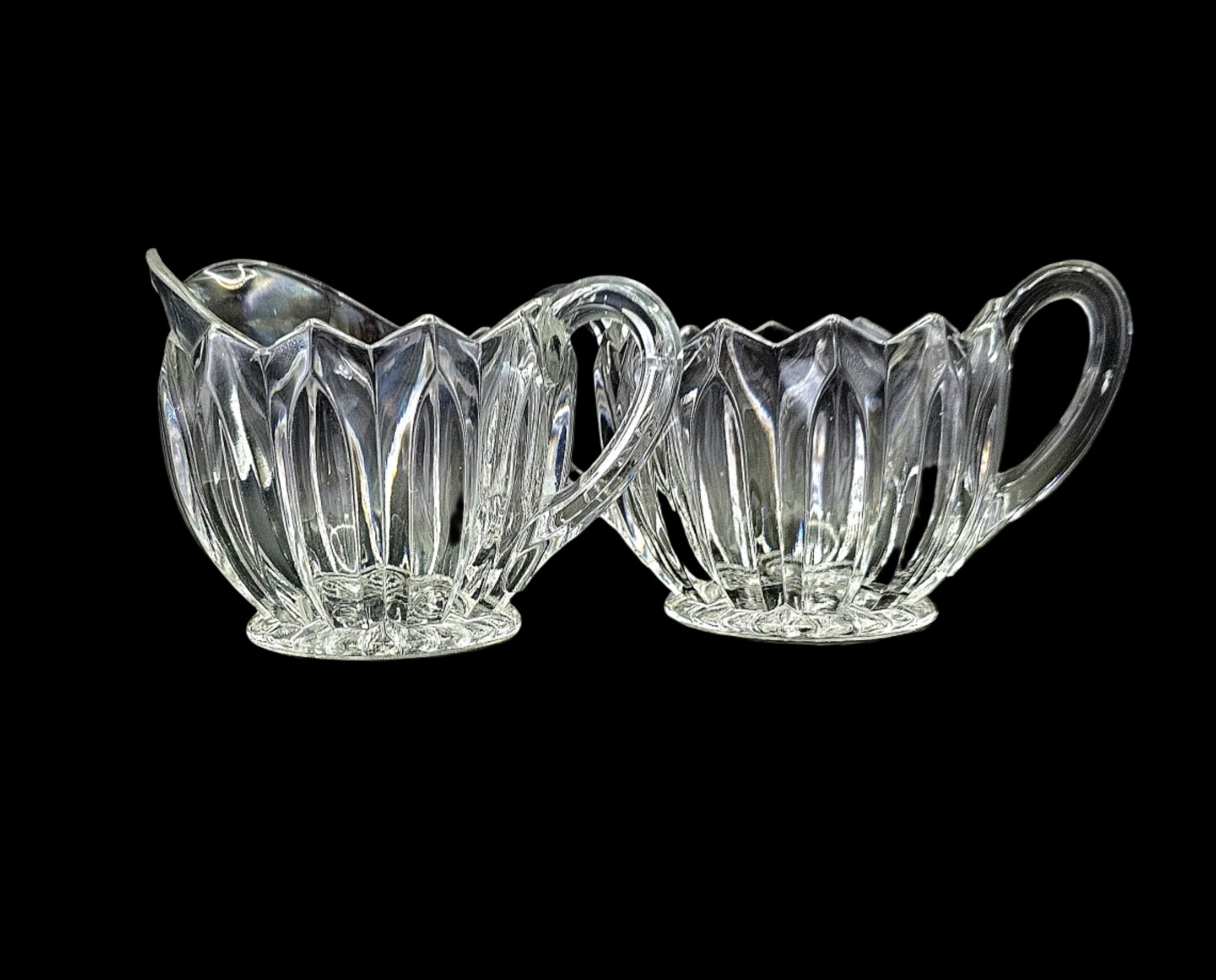 Glass sugar and creamer set, with handles, scalloped edge, and fluted sides.