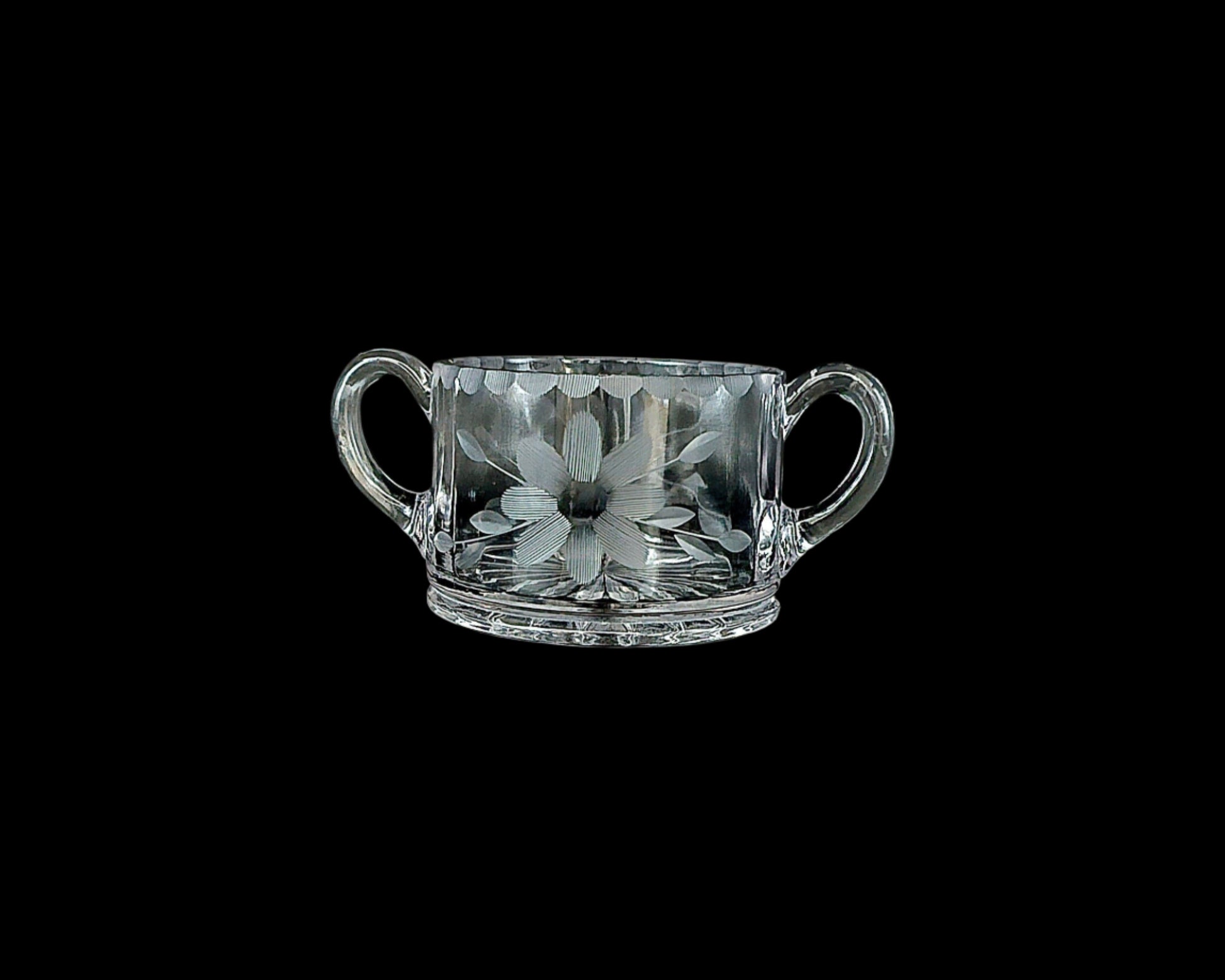 Two handled vintage glass sugar bowl. Etched with what may be a daisy pattern with leaves. Scalloped etchings along the edge.