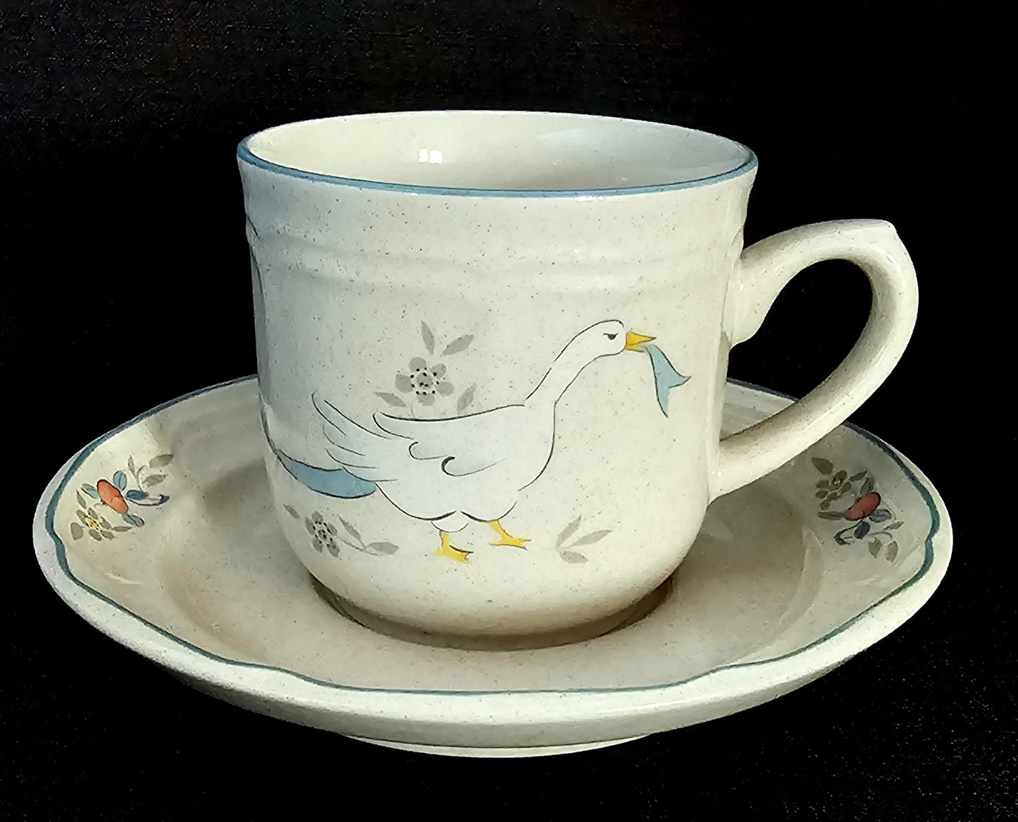 International Tableworks &quot;Marmalade&quot; pattern cup and saucer set with white geese, light blue ribbon and edging, and red fruit.