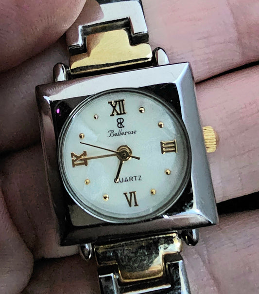 Square Bellerose Italy women&#39;s watch with a stainless steel case and silver-and-gold toned metal link band. The face appears to be mother of pearl. Twelve, three, six, and nine o&#39;clock designations are in gold Roman numerals.