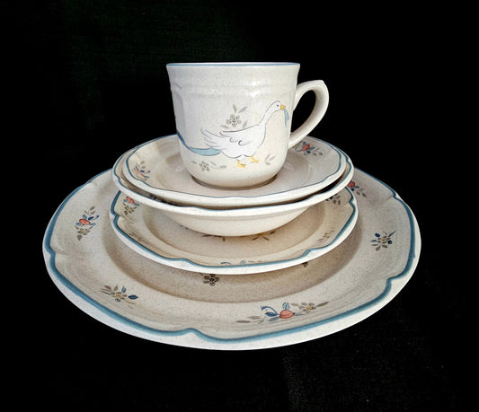 Stack of International Tableworks Stoneware in Marmalade pattern. Dinner plate, salad plate, cereal bowl, saucer, and cup stacked from largest on bottom.